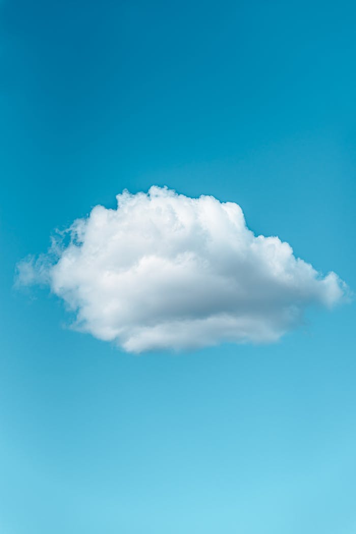 Low angle of lonely white fluffy cloud floating in blue sky in sunny day
